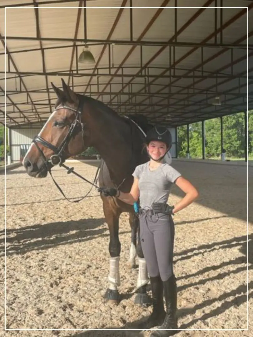 A woman standing next to a horse in an arena.