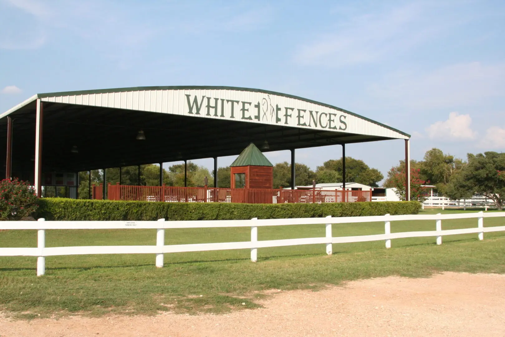 A white fence with a red and green building in the background.