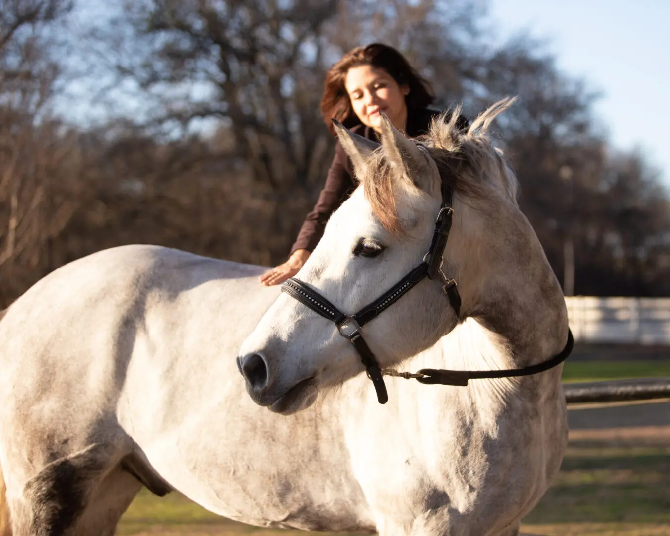 A woman riding on the back of a white horse.