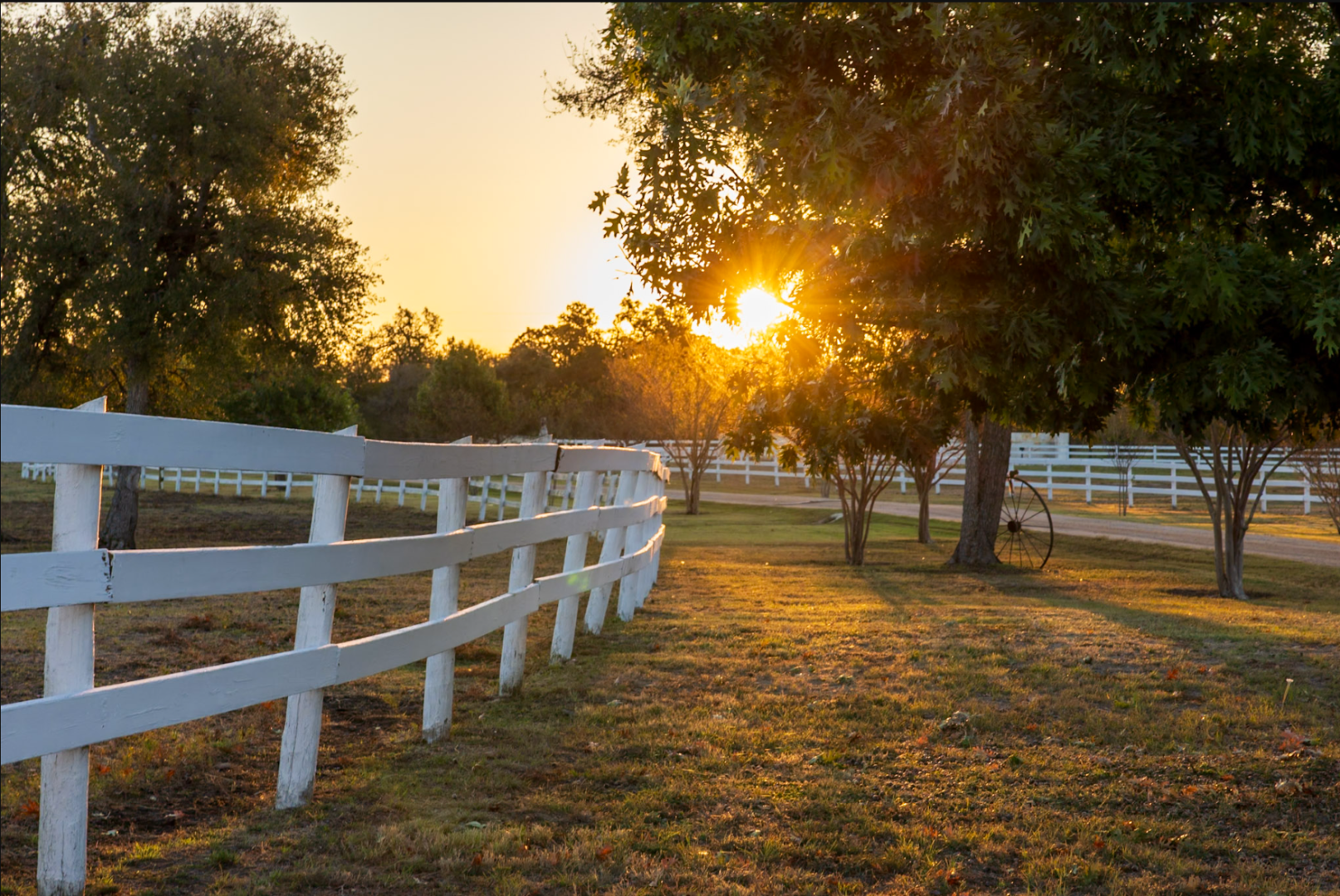 A white fence in the middle of an open field.